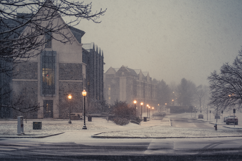 Two grey Hokie Stone buildings on a snowy evening. 
