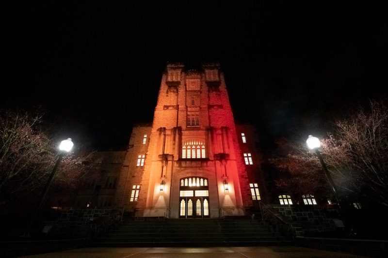 Burruss Hall illuminated orange and maroon at nighttime. 